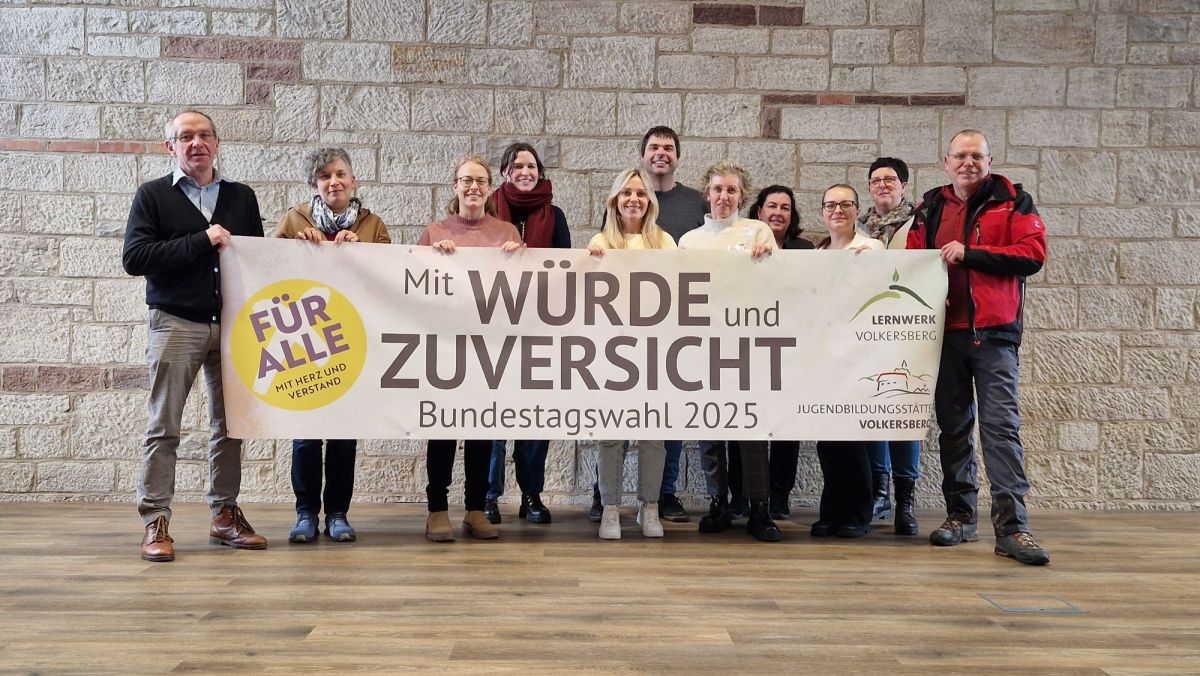 11 Menschen halten ein Werbebannder für die Bundestagswahl 2025